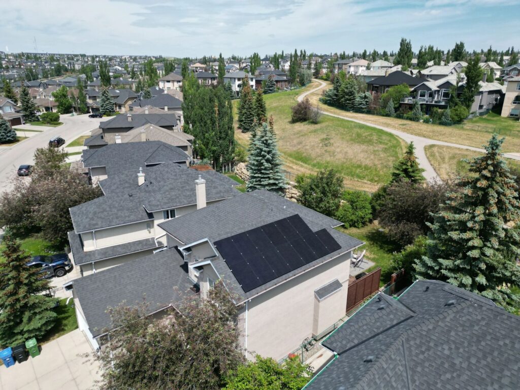 Aerial view of a suburban neighborhood with houses, green trees, manicured lawns, and a winding pathway through a grassy park area.