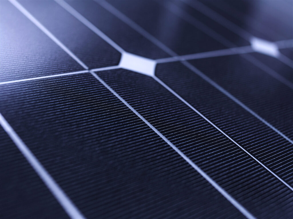 This image shows a close-up of a solar panel, highlighting the intricate patterns of silicon cells with metallic grid lines for energy collection.