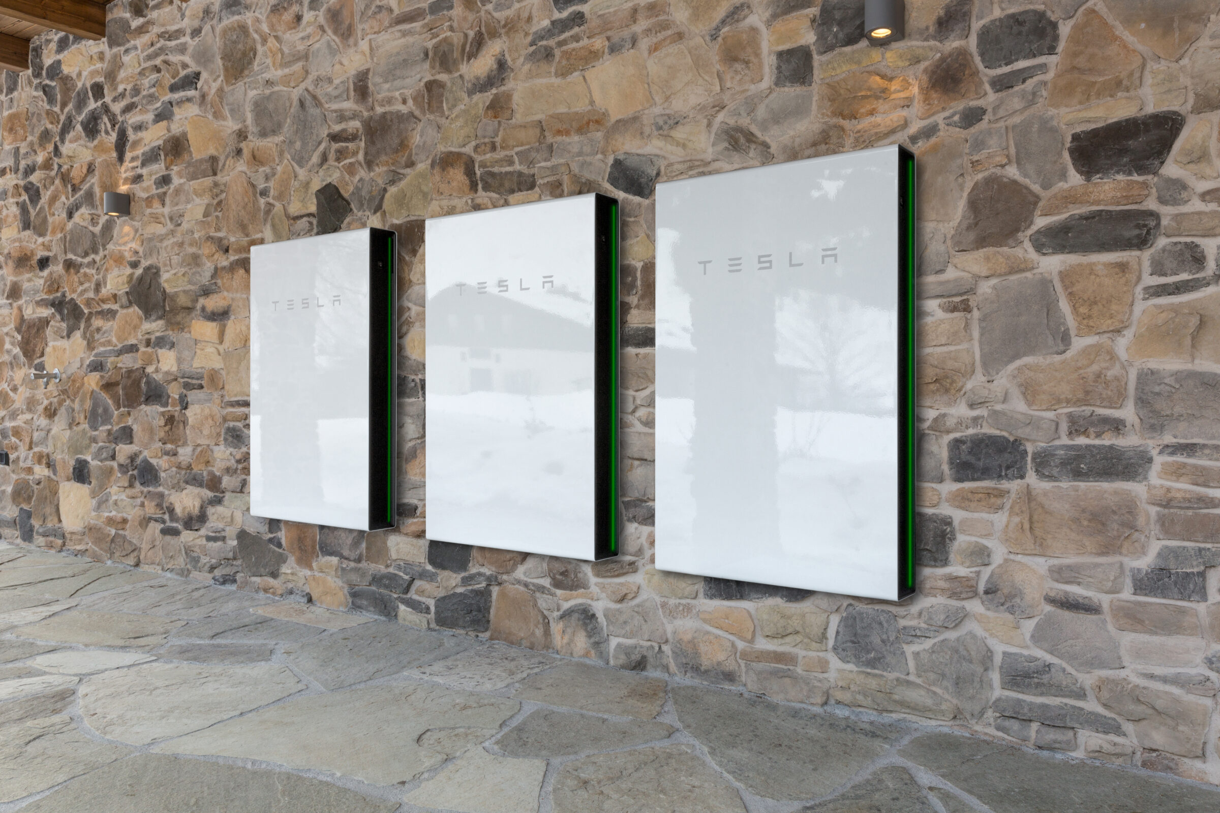 A group of Tesla Powerwalls on a stone wall