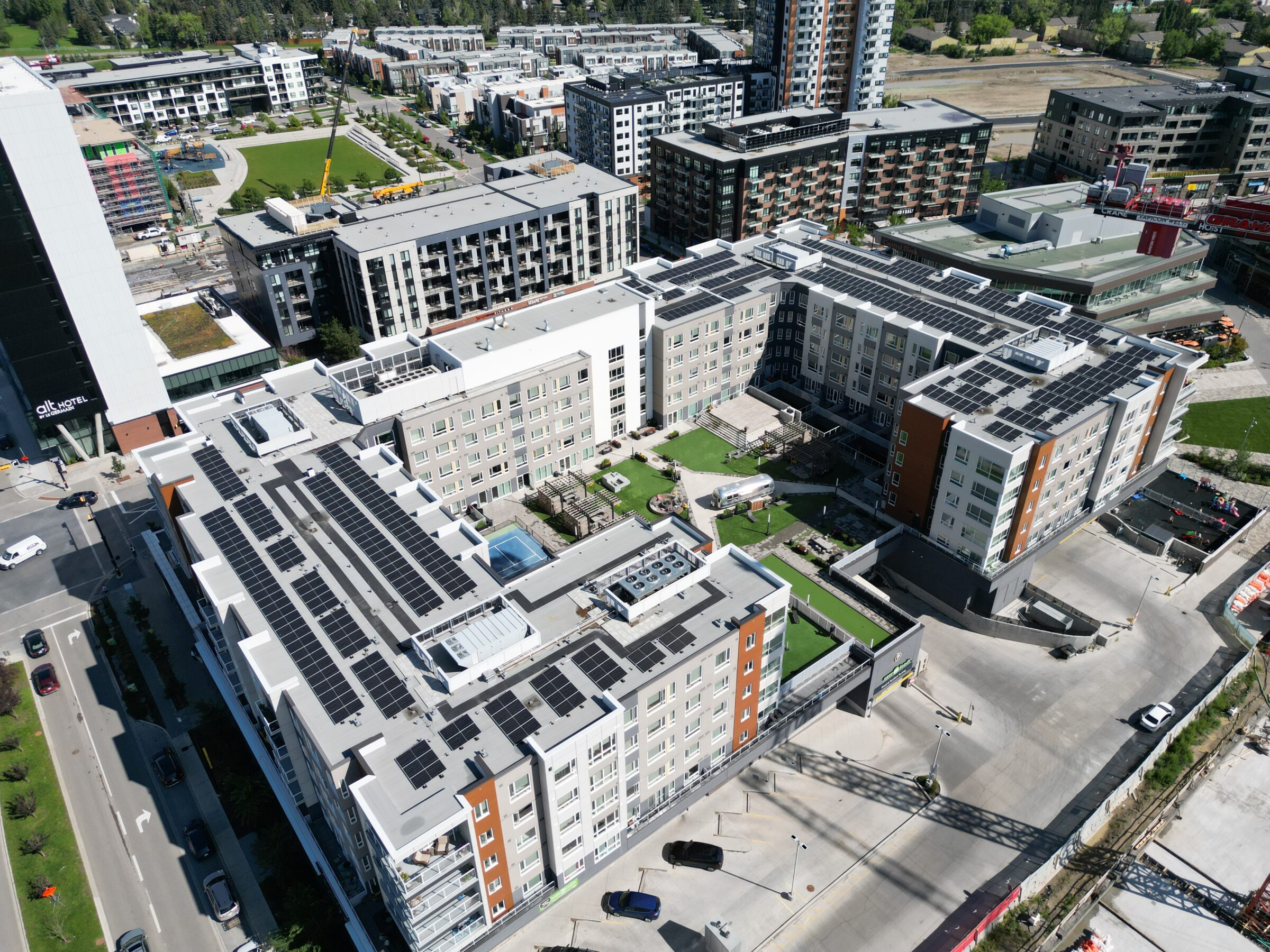 Solar array installed on the roof of a commercial mixed-use building with both apartments and commercial space, and a green living area in the middle.