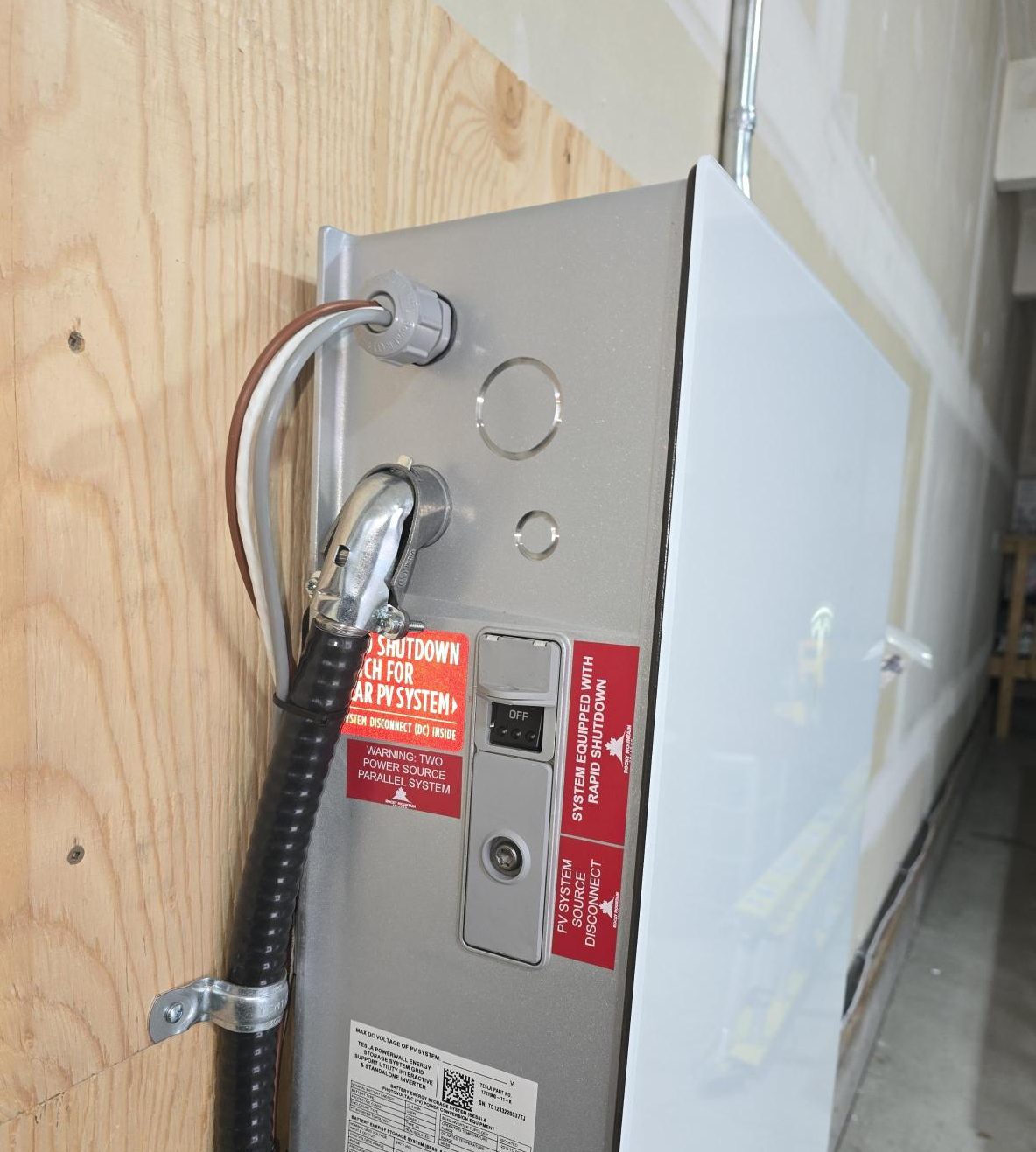 Certified Tesla Powerwall Calgary installer mounting an exterior backup battery for a residential solar system.
