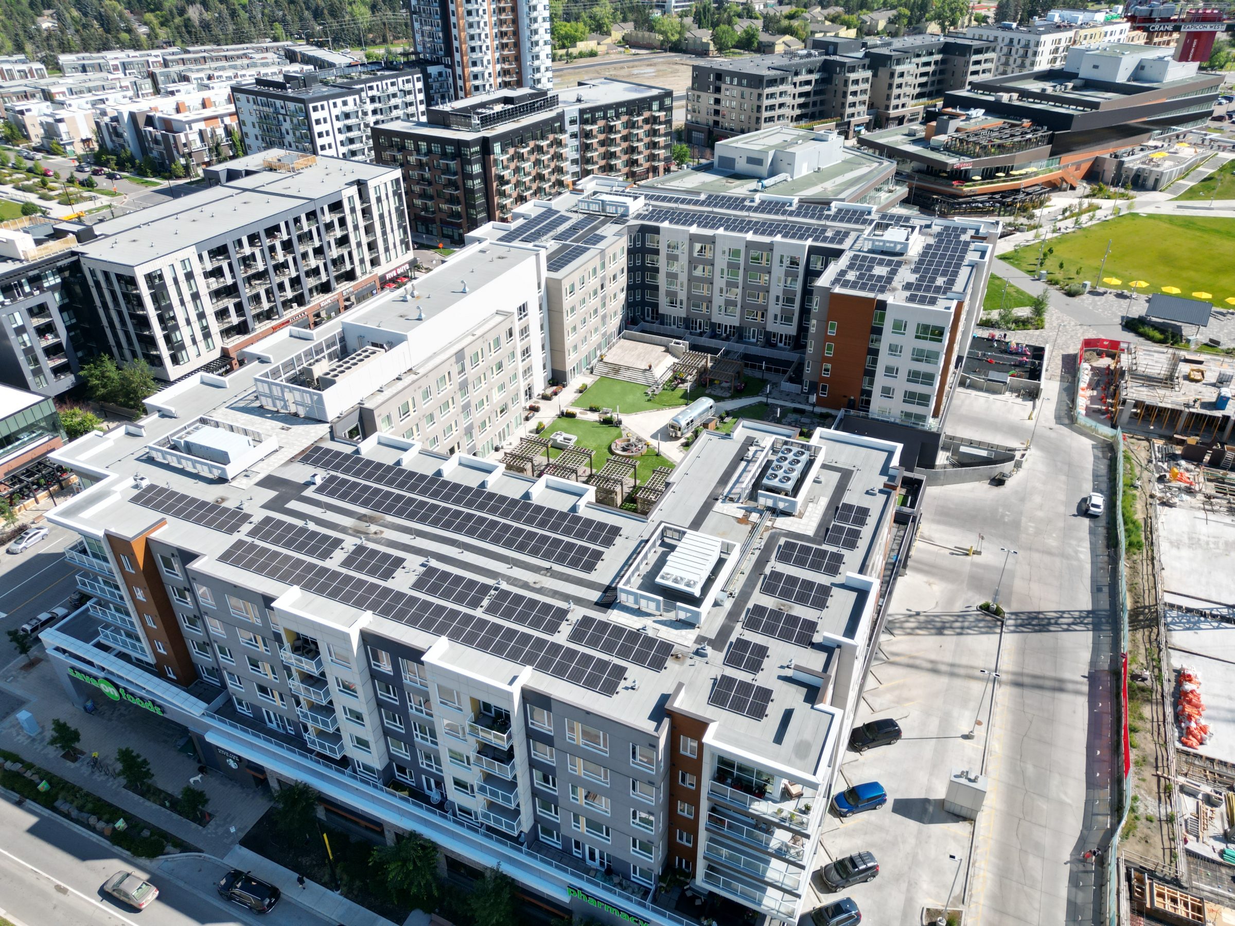 Aerial drone view of a high-efficiency commercial flat-roof solar panel array using a Soprasolar integrated PVC pedestal racking system by Rocky Mountain Solar Co.